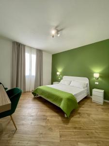 a bedroom with a large bed with a green wall at ALBARIA ROOMS-APARTMENTS in Marsala
