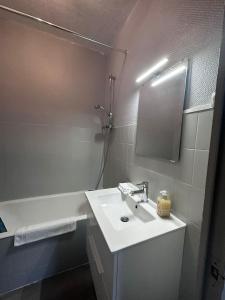 y baño blanco con lavabo y ducha. en Les Cosy De Nancy - L'alcove city trip 4 étoiles, en Nancy