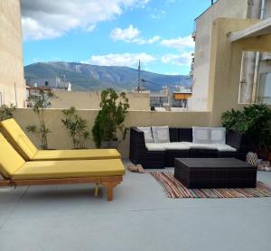 eine Terrasse mit Sofas und Stühlen auf dem Balkon in der Unterkunft INSPIRATION Guestroom with Amazing Roof Garden in Athen