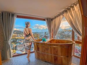 una donna in piedi in una vasca da bagno in una stanza con finestra di Casanova Dalat Hotel a Da Lat