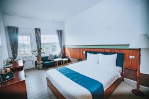 Cette chambre comprend un grand lit et deux fenêtres. dans l'établissement Casanova Dalat Hotel, à Đà Lạt