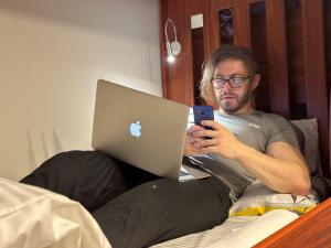 Un uomo seduto a letto che guarda il suo cellulare di Business Backpackers JBR (BBJ) a Dubai