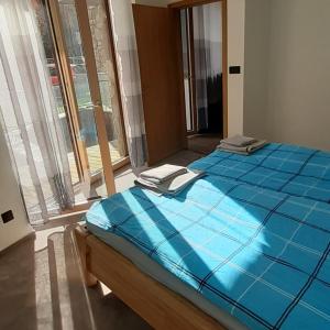 duże niebieskie łóżko w pokoju z oknem w obiekcie Apartmán 107 Ovruč w Szczyrbskim Plesie