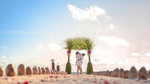 a person standing next to a palm tree on a beach at Malahini Kuda Bandos Resort in North Male Atoll