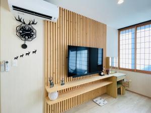 a living room with a television on a wall at 東瀛Stays402奈良　お洒落な和洋室 in Osaka