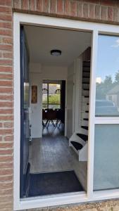 a sliding glass door of a house with a patio at Gezellig 6pers Familiehuis grote tuin met BBQ aan meer Gelderland in Ewijk