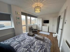 a bedroom with a bed and a chair and windows at Seapoint House in Cleveleys