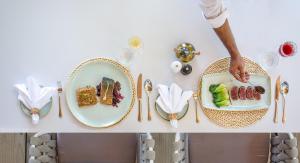 a man standing next to plates of food on a table at Malahini Kuda Bandos Resort in North Male Atoll