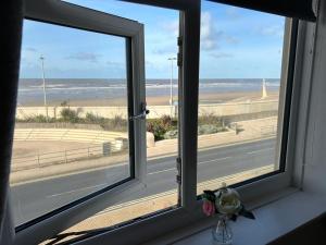 een raam met uitzicht op de oceaan vanaf een strand bij Seapoint House in Cleveleys