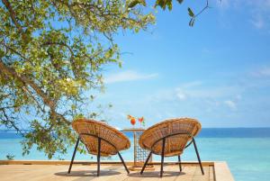 two chairs sitting on a table near the ocean at Malahini Kuda Bandos Resort in North Male Atoll