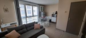uma sala de estar com um sofá e uma cozinha em Appart T2 standing tout confort avec balcon - parking en option em Lyon