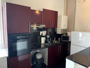 une cuisine avec des placards violets et un comptoir noir dans l'établissement Agréable maison de ville dans la plus belle Avenue, à Orléans