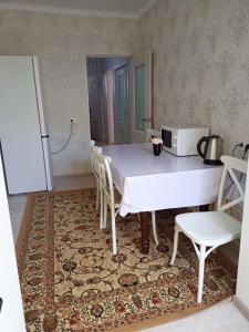 einen weißen Tisch mit Stühlen und eine Mikrowelle auf einem Teppich in der Unterkunft 2 комнатная в микрорайоне Шугыла in Qysylorda