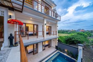 a house with a balcony and a swimming pool at Kasmaran Bali Guest House in Munggu