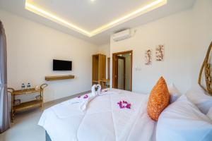 a room with a white bed and a couch at Kasmaran Bali Guest House in Munggu