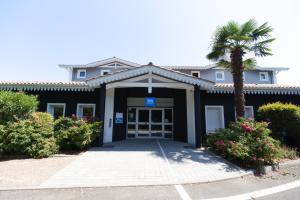 a building with a palm tree in front of it at ibis Budget La Teste Bassin d'Arcachon in La Teste-de-Buch