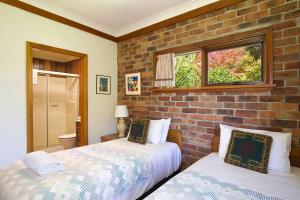 2 camas en una habitación con una pared de ladrillo en Stableford Lodge, en Blackheath
