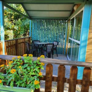 - une terrasse couverte avec des chaises, une table et des fleurs dans l'établissement La Tour du Loup, à La Bastide-de-Sérou