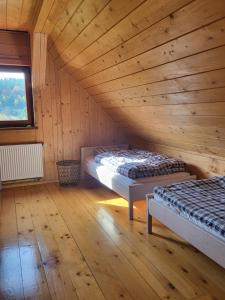a room with two beds in a wooden cabin at Willa Wirchnia in Małastów