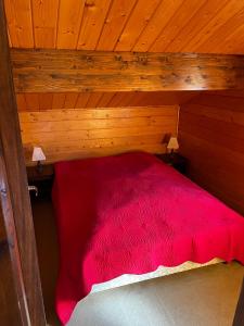 a bedroom with a red bed in a wooden room at Chalet calme cosy Eyne station 2600 in Eyne