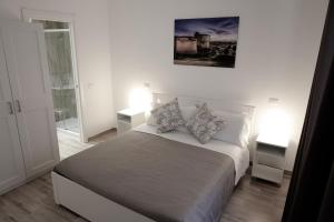 a white bedroom with a bed and two night stands at Central Guest House in Civitavecchia