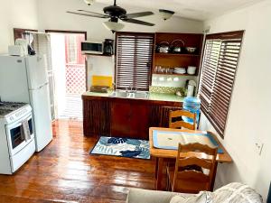 a kitchen with a table and a white refrigerator at Hummingbirds Cabins in Caye Caulker