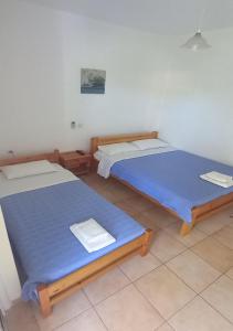 2 Betten in einem Zimmer mit blauer Bettwäsche in der Unterkunft Glaros Studios in Loutra Edipsou