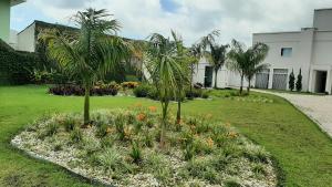 a garden with palm trees and flowers in a yard at Apartamento completo no centro de Tijucas 105 in Tijucas