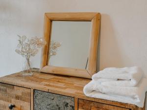 a mirror on top of a wooden dresser with towels at Maison de village dans le Luberon in Oppedette