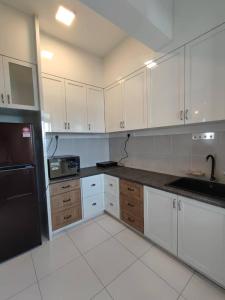 a kitchen with white cabinets and a black refrigerator at Mint Cabin @ Oasis Condo Ipoh in Ipoh