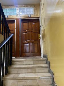 une porte en bois avec des escaliers en face d'un bâtiment dans l'établissement Departamento amoblado centro Manta, à Manta