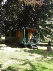 uma pequena cabana com um alpendre num parque em La Roulotte du Moulin de Rebets 