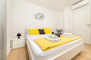 1 dormitorio blanco con 1 cama grande con almohadas amarillas en Sun Residence Krk, en Krk