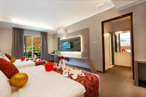 pokój hotelowy z 2 łóżkami i telewizorem w obiekcie Lavigo Resort w mieście Pantai Cenang