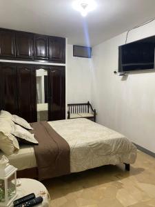 Schlafzimmer mit einem Bett und einem Flachbild-TV in der Unterkunft Departamento amoblado centro Manta in Manta