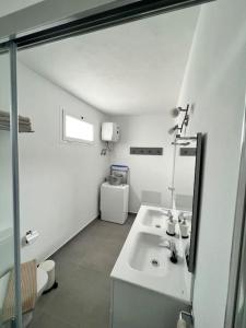 uma casa de banho branca com um lavatório e um espelho em El Cercado em Tinajo