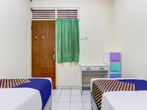 Zimmer mit 2 Betten und einem grünen Vorhang in der Unterkunft OYO Life 91374 Asia Stay Semarang Syariah in Semarang