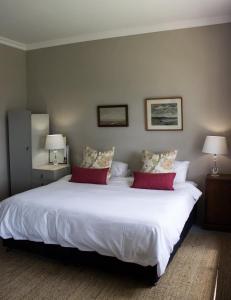 una camera da letto con un grande letto bianco con cuscini di Mill Cottages a Henburg Park