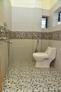 a bathroom with a toilet and a tiled floor at Jardim a Mar in Agonda