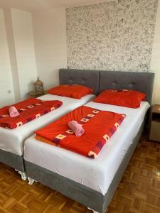 two beds in a bedroom with red pillows at Guest House Husejn in Dubrave Gornje