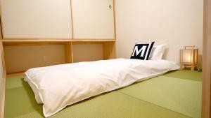- un lit blanc avec une chaise au-dessus dans l'établissement 東瀛Stays402奈良　お洒落な和洋室, à Osaka