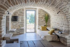 a room with a stone wall with a couch and a window at La Maison de Louise in Colombiès