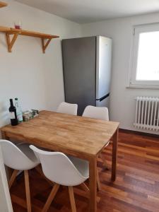 einen Esstisch mit weißen Stühlen und einen Kühlschrank in der Unterkunft Appartment Himmelblau in Friedrichshafen