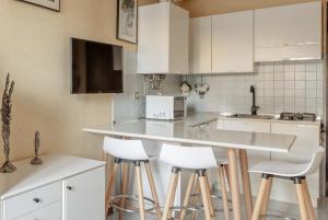 a kitchen with white cabinets and bar stools at Il Cavalluccio in Grado