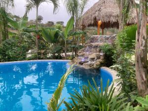 a swimming pool in a resort with a waterfall at Hotel La Costa International in Puerto López
