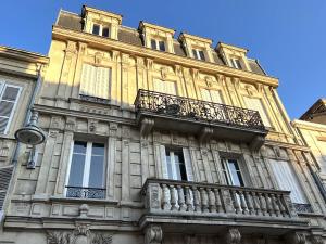 un grande edificio con balcone sul lato di l'Hôtel des Ventes Reims Chativesle a Reims