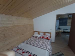 Bett in einem Zimmer mit einer Holzwand in der Unterkunft La cabana in Ocnele Mari