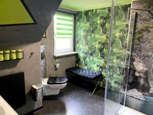 ein Bad mit einer Dusche, einem WC und einer grünen Wand in der Unterkunft im Haus zur Auszeit willkommen in Ruhla