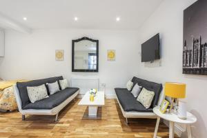 a living room with two couches and a tv at Deluxe Flat A in Kensington Olympia in London