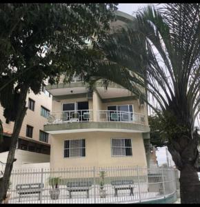 a building with a balcony and benches in front of it at Apê Temporada Vila Guilhermina in Praia Grande